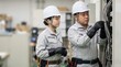 © 望見 柿元 - 配電盤の点検作業で安全教育を受ける絶縁手袋をした日本人男女の電気工事士