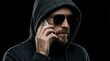 © Masque - A mysterious man in a dark hoodie and sunglasses making a phone call to impersonate a trusted source.