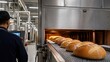 © Maryia - Commercial bakery oven output concept showing shift supervisor manufacturer inspecting loaf bread on conveyor after tunnel oven highlighting quality control large scale baking food production