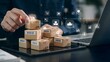 © Abu - Close-up of a person arranging small delivery boxes stacked on a tablet device, with digital icons representing e-commerce and logistics overlaid