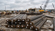 © Logo - Large stacks of steel rebar materials at industrial construction site under cloudy sky development.