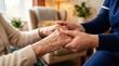 © Ievgeniia - Close-up of a caregiver holding an elderly person’s wrinkled hands in a cozy home setting, showing compassion, support, and senior care during a gentle moment
