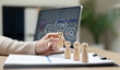 © Father_Studio - Employee training and professional development concept with wooden figures, digital learning icons and laptop. Workforce education, skill improvement, leadership training and talent management.