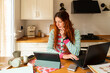 © Alba Vitta Studio/Stocksy - Woman Works on Tablet and Laptop at Kitchen