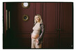 © Nata Segueza/Stocksy - Expecting mother poses in a room with dark walls