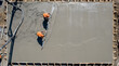 © raiyan.md - Team of professional construction contractors leveling and screeding a freshly poured wet cement concrete slab foundation on a residential building site using manual tools
