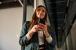 © Ivan Jovanovic/Stocksy - Beautiful woman holds a mobile phone inside the corporation