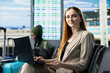 © DC Studio - Portrait of female CEO waiting in airport terminal for business trip with formal wear, attending international business summit and traveling by plane, Passenger preparing for flight departure.