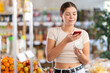 © JackF - Young woman buyer scanning qr code for canned food in grocery store