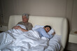 © DimaBerlin - Exhausted elderly married lying in bed with frustration and disappointment after arguing, senior husband and wife holding out offence and disagreement, partners growing apart after crisis.
