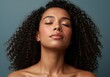 © Breezze - Young woman with curly hair and water droplets on her skin tilting head back for holistic spa, beauty products and wellness brand advertising on a blue background