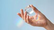 © Sohail - Hand holding clear glass prism cube casting vibrant rainbow light refractions on soft blue background