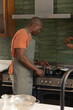 © wavebreak3 - Gas range is heating saucepan while frying pan is sizzling by dark green backsplash with colander