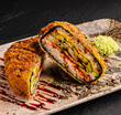 © AntAlexStudio - Two halves of deep fried crispy sushi burger are served on a plate. Delicious Asian fusion dish is filled with eel, avocado and sweet unagi sauce.