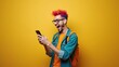© Nataliia_Trushchenko - Young man with colorful hair wearing glasses smiles while holding smartphone against a bright yellow background, showcasing casual attire and vibrant style