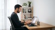 © m0lydar - A man sits at a desk typing on a laptop in a well-lit room.
