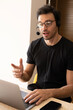 © Rafael - Vertical portrait of a customer service agent explaining information while looking at a computer screen.