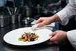 © Maxime - Chef cuisinier nettoyant méticuleusement le bord d'une assiette avant le service