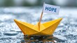 © ladaz - Bright yellow paper boat with hope flag floating on water surface