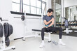 © ChauBich - Young man with shoulder pain resting on bench after workout in gym