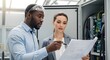 © Marina - Engineers discuss a schematic diagram in front of an open electrical control panel. AI generated.