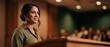© Fernando - Confident female speaker public speaking at podium in auditorium presenting to audience with smile, professional young indian woman lecturer, business presentation, conference seminar education forums