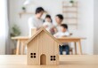 © bk - Wooden house model with happy family in background