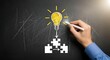 © SABYDA - Hand light bulb and puzzle pieces on blackboard representing idea generation and problem solving chalk