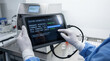 © Alice_Fame - Biomedical specialist runs firmware diagnostic on rugged tablet connected via data cable to automated tissue processor. Firmware installation progress. Repair equipment. Diagnostic system. Copy-space.