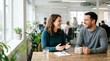 © Xenia - Friendly colleague chat in a modern office. Smiling man and woman having a casual business discussion at a wooden table. Teamwork and workplace communication concept