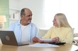 © New Africa - Pension. Senior couple with paperwork, laptop and calculator at table indoors