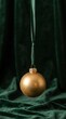 © AdPremium - Elegant Gold Christmas Bauble Hanging on a Green Ribbon Against Dark Velvet