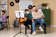 © Pixel-Shot - Happy father and son learning guitar together with music sheets in a bright home studio