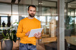 © Westend61 - Confident businessman with tablet PC leaning on glass wall at office