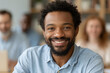 © lashkhidzetim - Man smiles warmly in a team meeting. Focused on work, he radiates positivity and confidence. Blurred colleagues suggest collaborative dynamics. Ideal for business, team, or motivational contexts