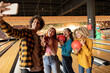 © Westend61 - Young man taking selfie through smart phone at bowling alley