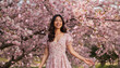 © jithin - Joyful Asian Woman in Floral Dress Laughing Among Falling Cherry Blossom Petals in Spring Garden