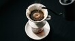 © Senja - Close-up shot of coffee being brewed using a pour-over method on a dark surface.