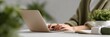 © KARINA - A woman is typing on a laptop in front of a potted plant