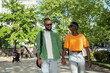 © DimaBerlin - Cheerful african american couple walks with hold hands in sidewalk downtown, guy makes girlfriend laugh by fun storytelling. Stylish black young woman enjoy stroll with happy boyfriend.