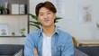 © blueringmedia - Smiling Young Asian Man with Crossed Arms in Modern Living Room
