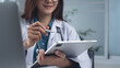© tippapatt - Female doctor using digital tablet at doctor's office. Doctor with stylus pen and tablet writing prescription, recording patient's health information