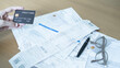 © Jokiewalker - Credit card on financial documents with receipts, pen and glasses, showing monthly bills, household expenses and credit card spending.