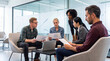 © Athena Studio - Diverse business team reviewing charts and documents during a focused collaborative meeting in an office lounge.