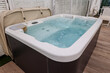 © Pixel-Shot - Outdoor hot tub with bubbling water and beige cover on a wooden deck for relaxation and wellness, the spa offers relaxation and wellness, providing a luxurious leisure experience