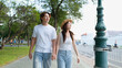 © blueringmedia - Young Asian Couple Holding Hands While Walking Along a City Sidewalk