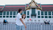© blueringmedia - Young Asian Couple Walking Past Ornate Thai Temple in Bangkok