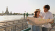 © blueringmedia - Young Asian Couple Reading Paper Map by Chao Phraya River