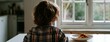 © Snowstudio - Child sitting at table looking out the window during meal