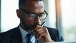 © Viktor - Focused businessman with glasses holds pen near mouth. Man in suit thinks deeply, considering important decision, analyzing data, planning strategy at work.